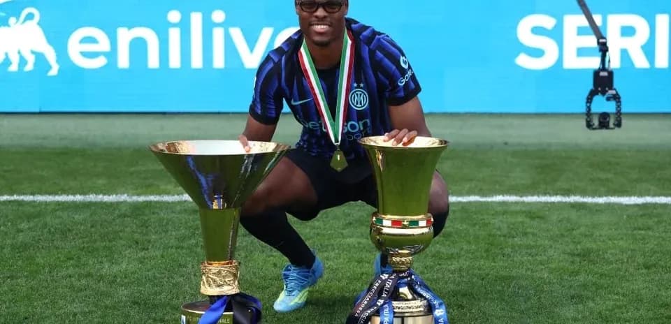 Player celebrating with two trophies on the field