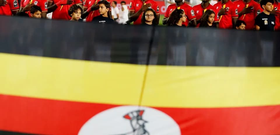 Ugandan players singing national anthem with flag