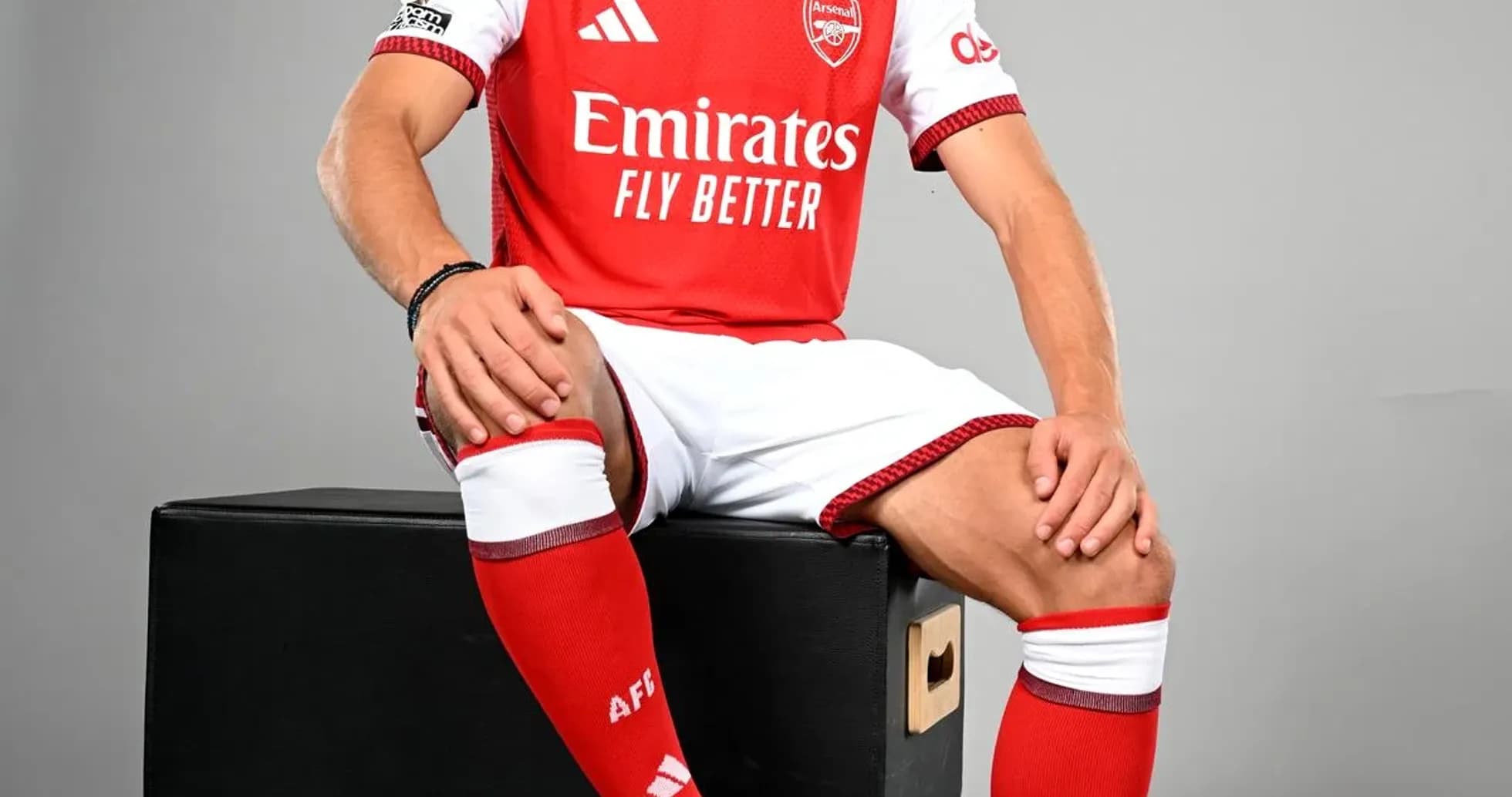Player in Arsenal kit sitting on box with ball