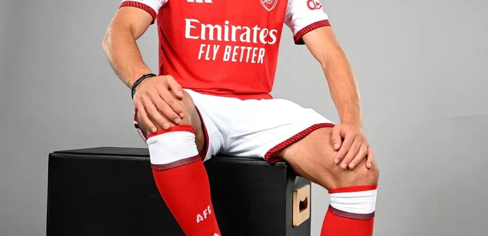 Player in Arsenal kit sitting on box with ball
