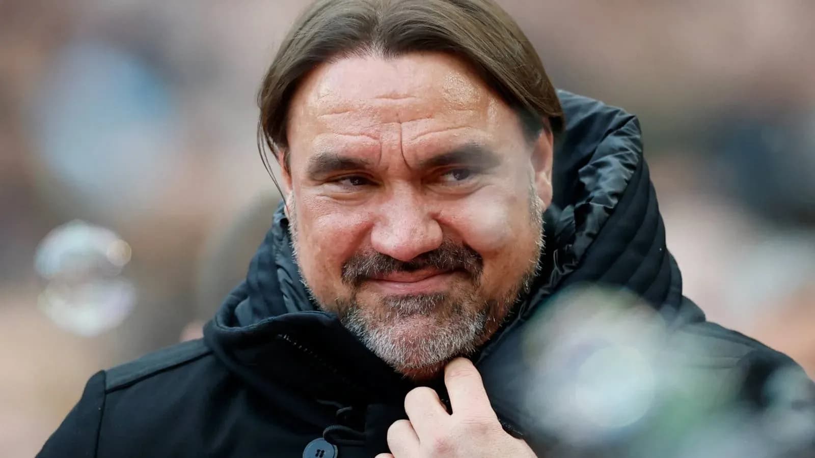 Man in black jacket with long hair smiling