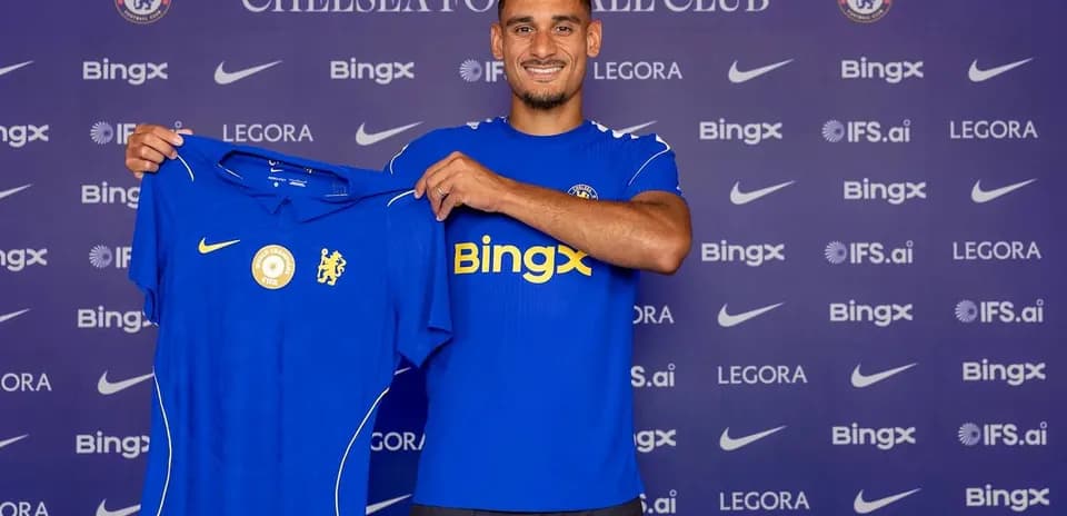 Player holding Chelsea jersey at press conference