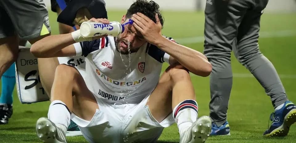 Player sitting on pitch pouring water on face