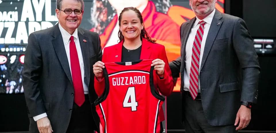 New coach holding jersey at press conference