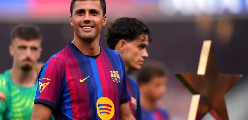 Player smiling while holding a trophy on field