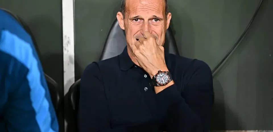 Coach sitting on bench during match, looking thoughtful