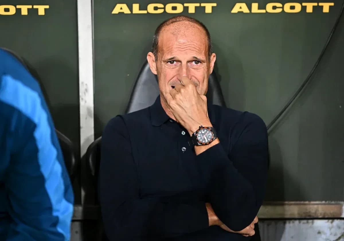 Coach sitting on bench during match, looking thoughtful