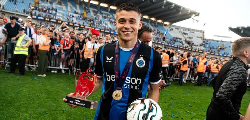 Player holding trophy and ball surrounded by fans