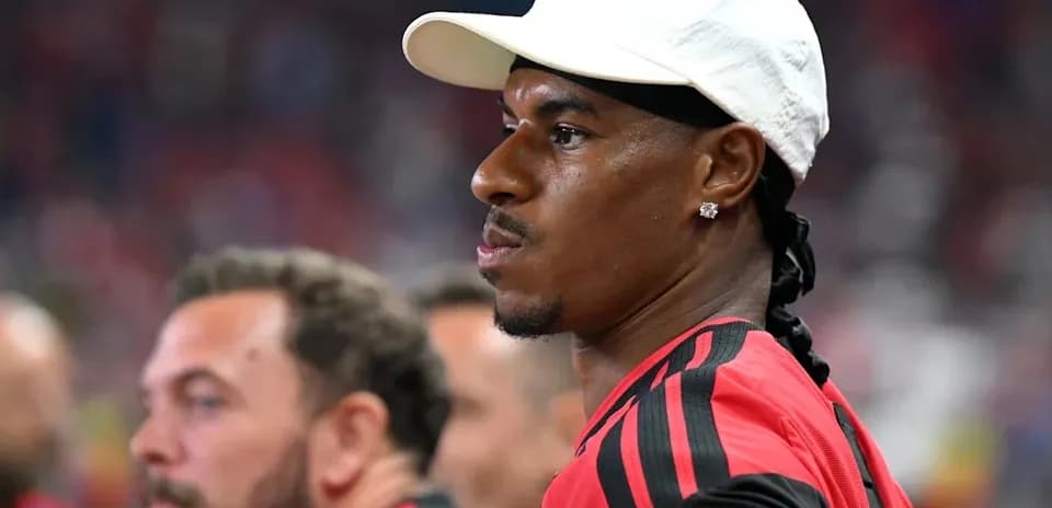 Player in red jersey and white cap on sidelines