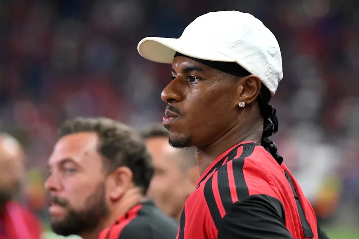 Player in red jersey and white cap on sidelines
