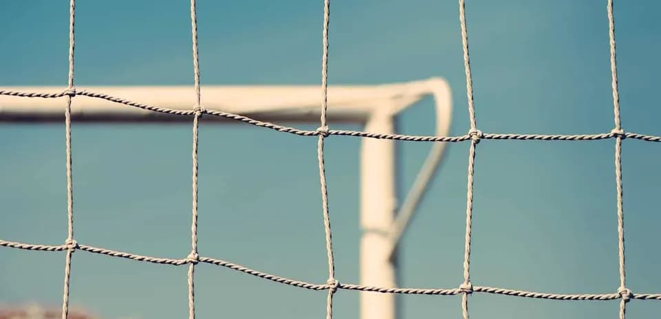 Close-up of soccer net with goalpost in background