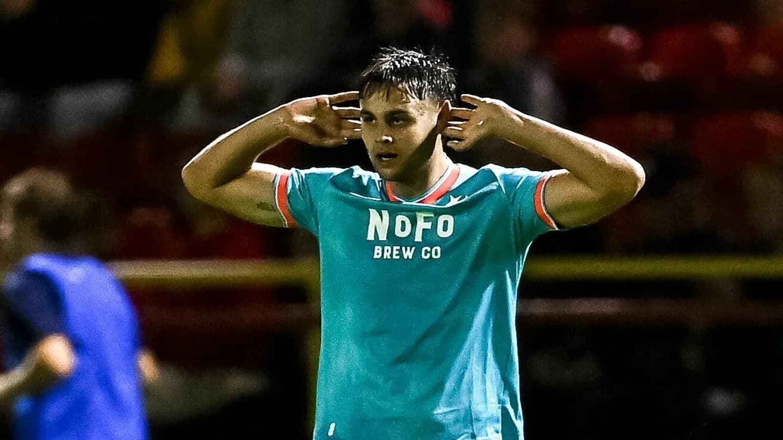 Player gesturing with hands to ears on field