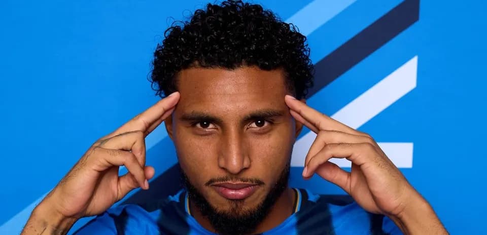 Player posing with hands on head against blue background