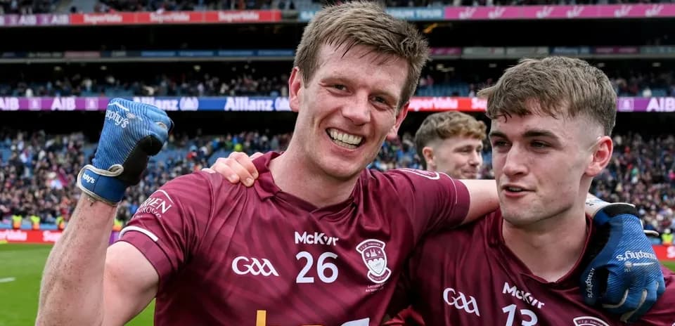 Two players celebrating in maroon jerseys after match