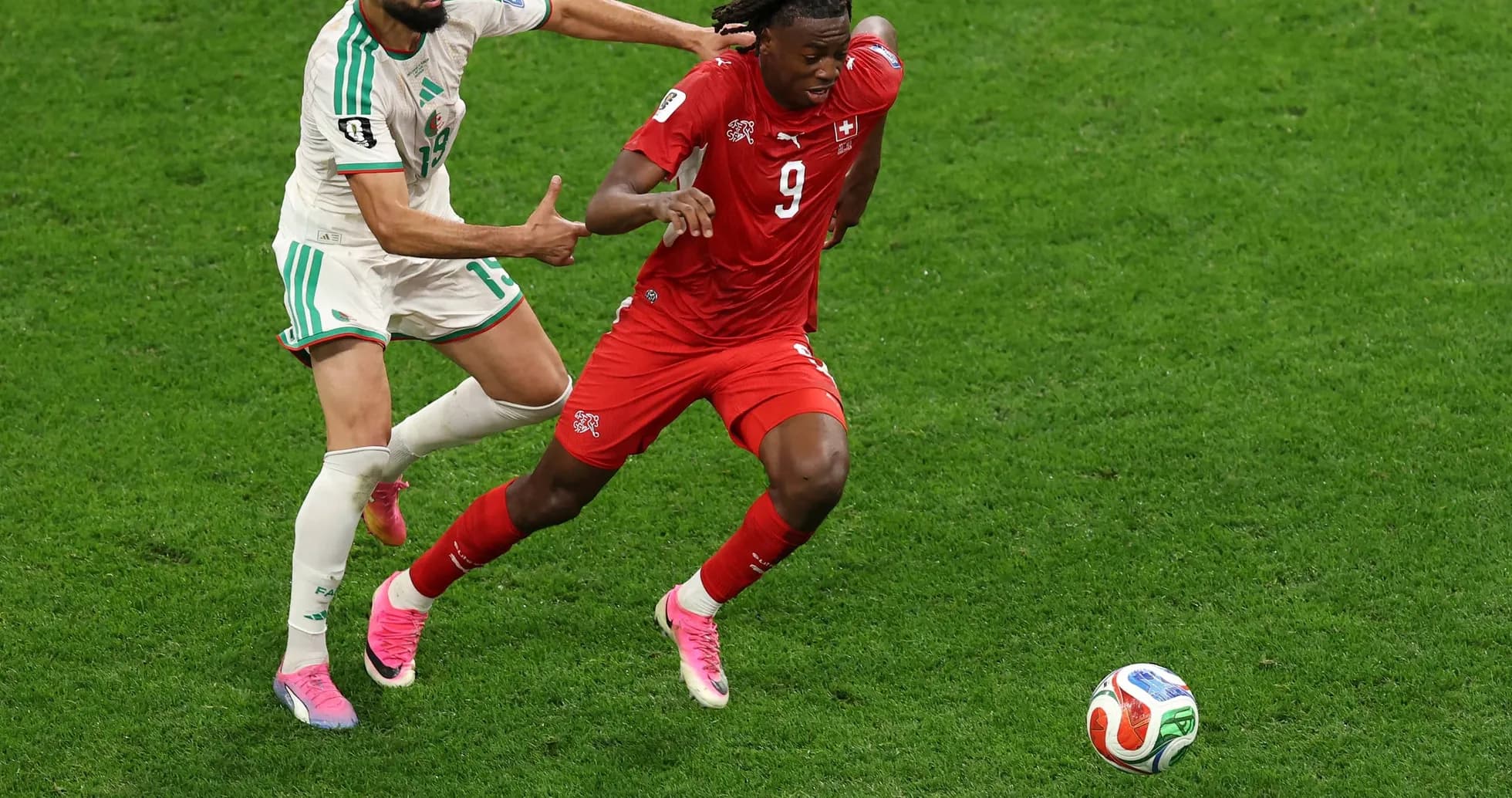 Swiss player evading Algerian defender during match