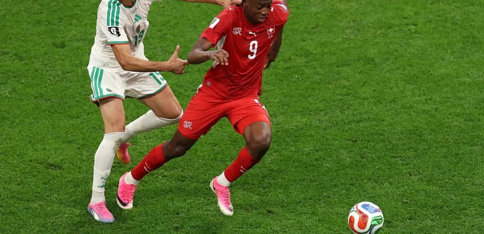 Swiss player evading Algerian defender during match