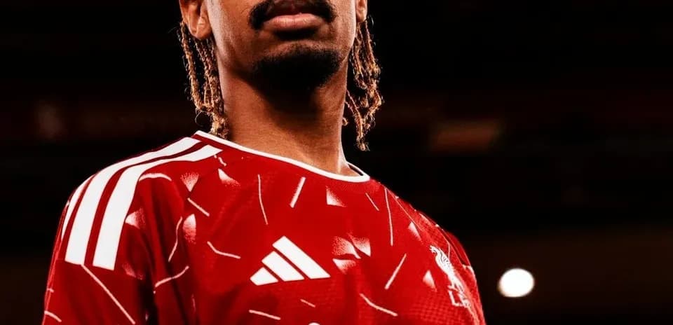 Player posing in red football kit with logo