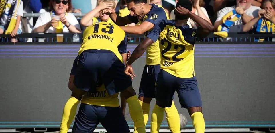 Players celebrating a goal with fans in background