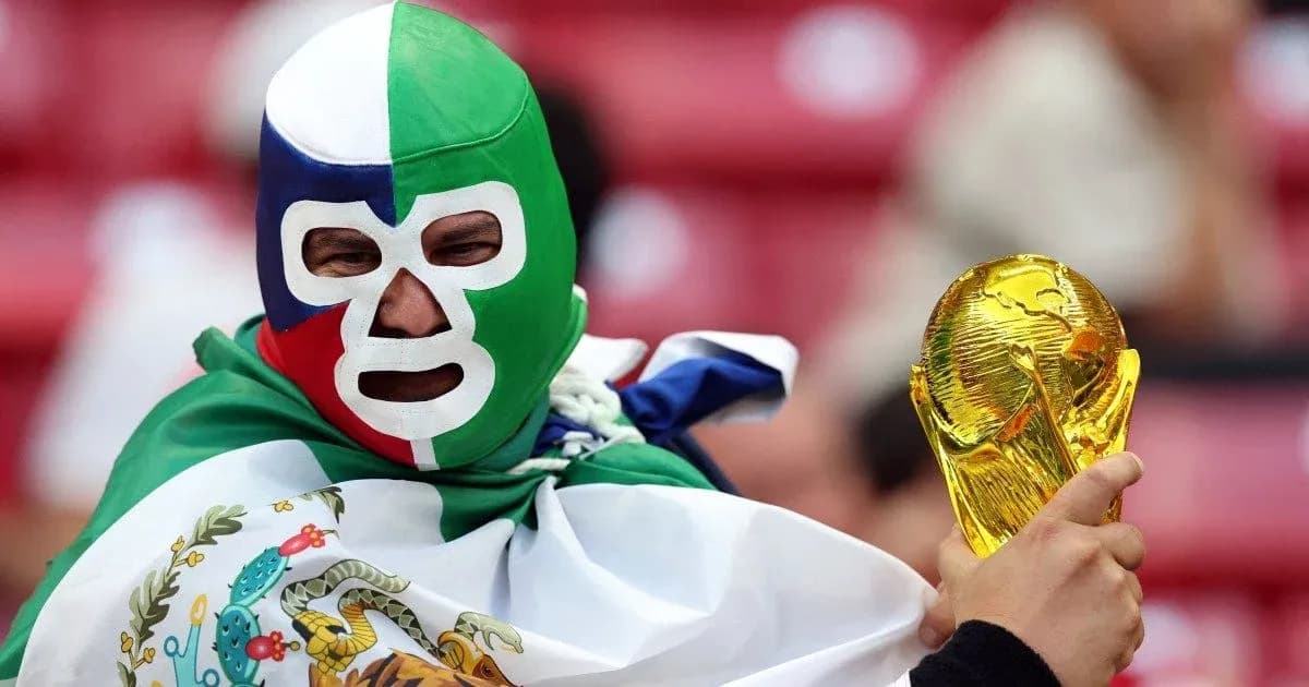 Fan in mask holding FIFA World Cup trophy