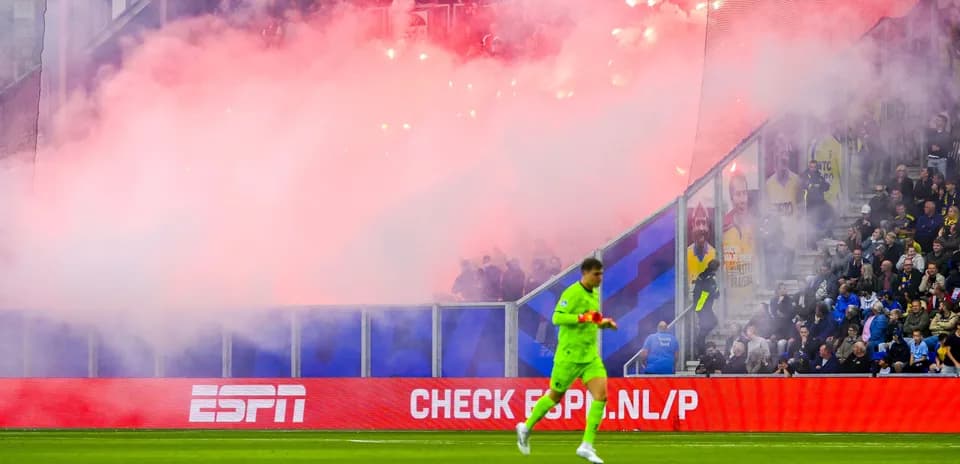 Goalkeeper walking past smoke and flares during match