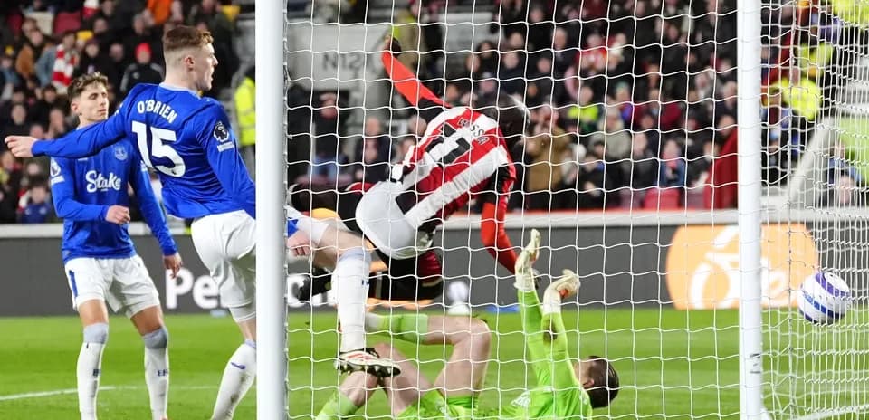 Brentford player scoring against Everton goalkeeper