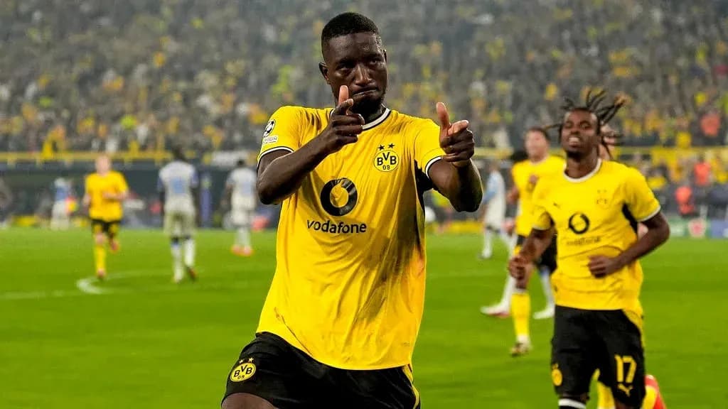 Player celebrating a goal with teammates in stadium