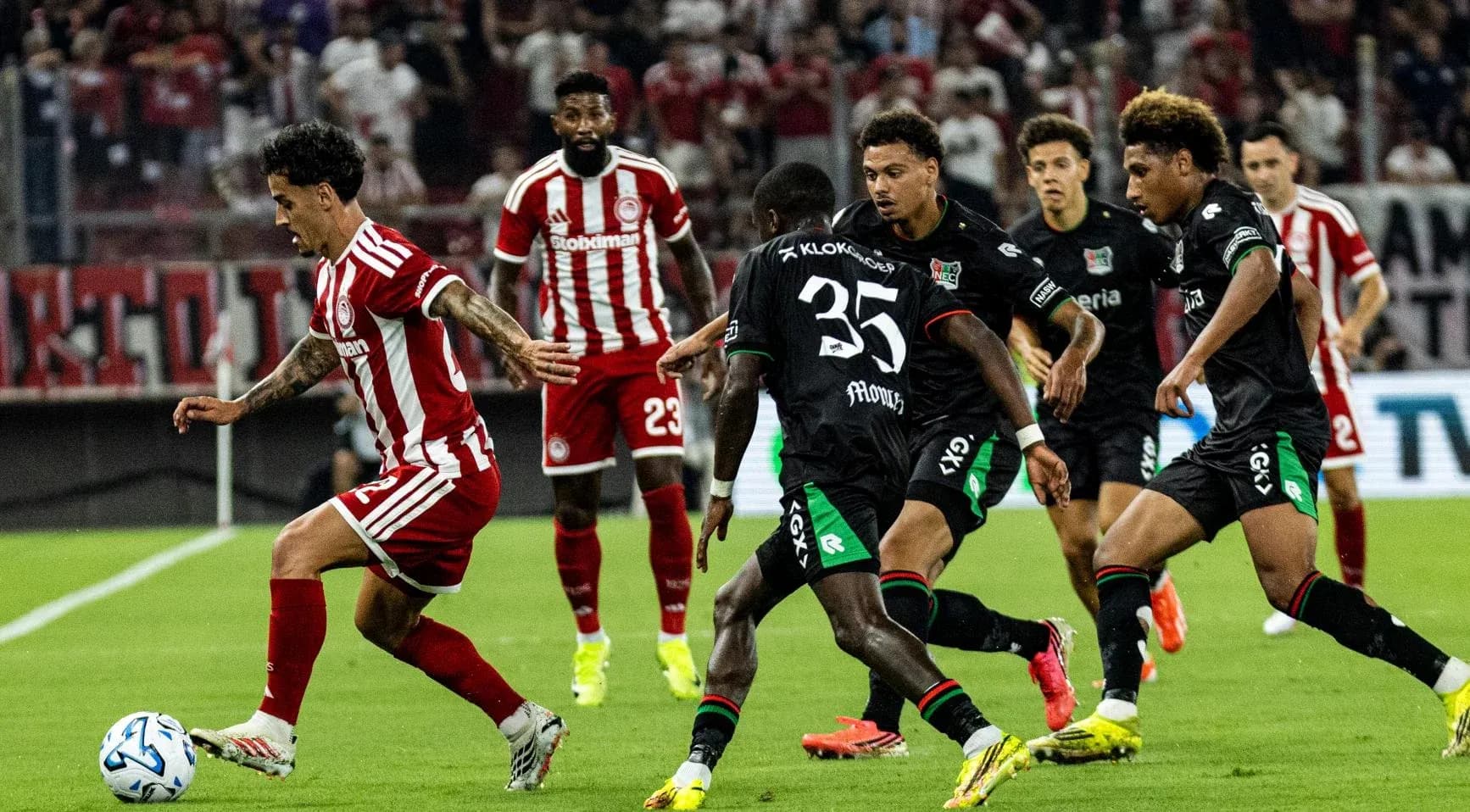 Olympiakos player dribbling past NEC defenders