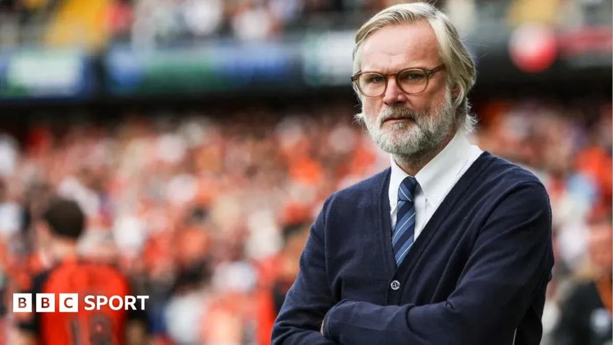 Coach observing match with arms crossed in stadium