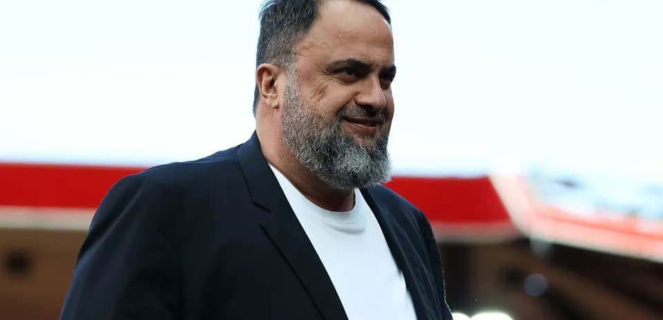 Man in black blazer smiling at stadium entrance