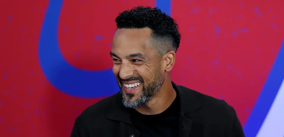 Man smiling during a media event backdrop