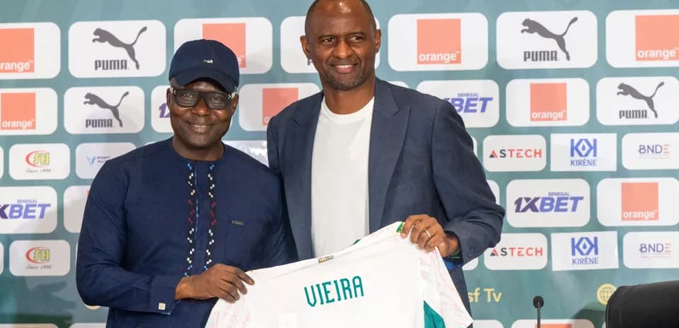 Two men holding a football jersey at press conference