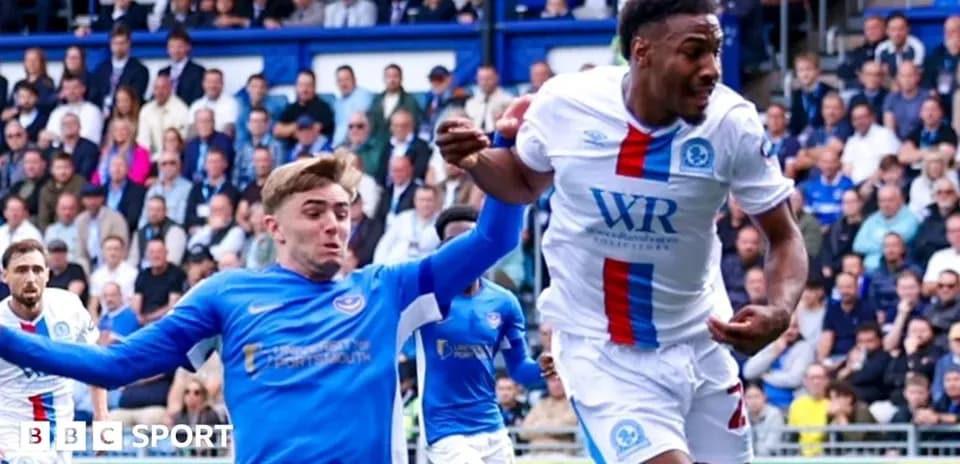 Player in blue jersey challenging player in white jersey