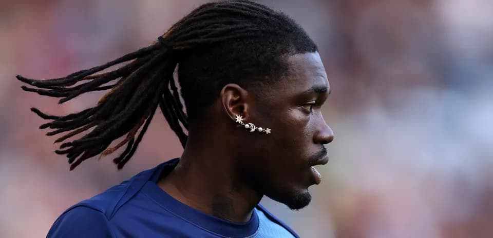 Player with long hair and unique earrings on field