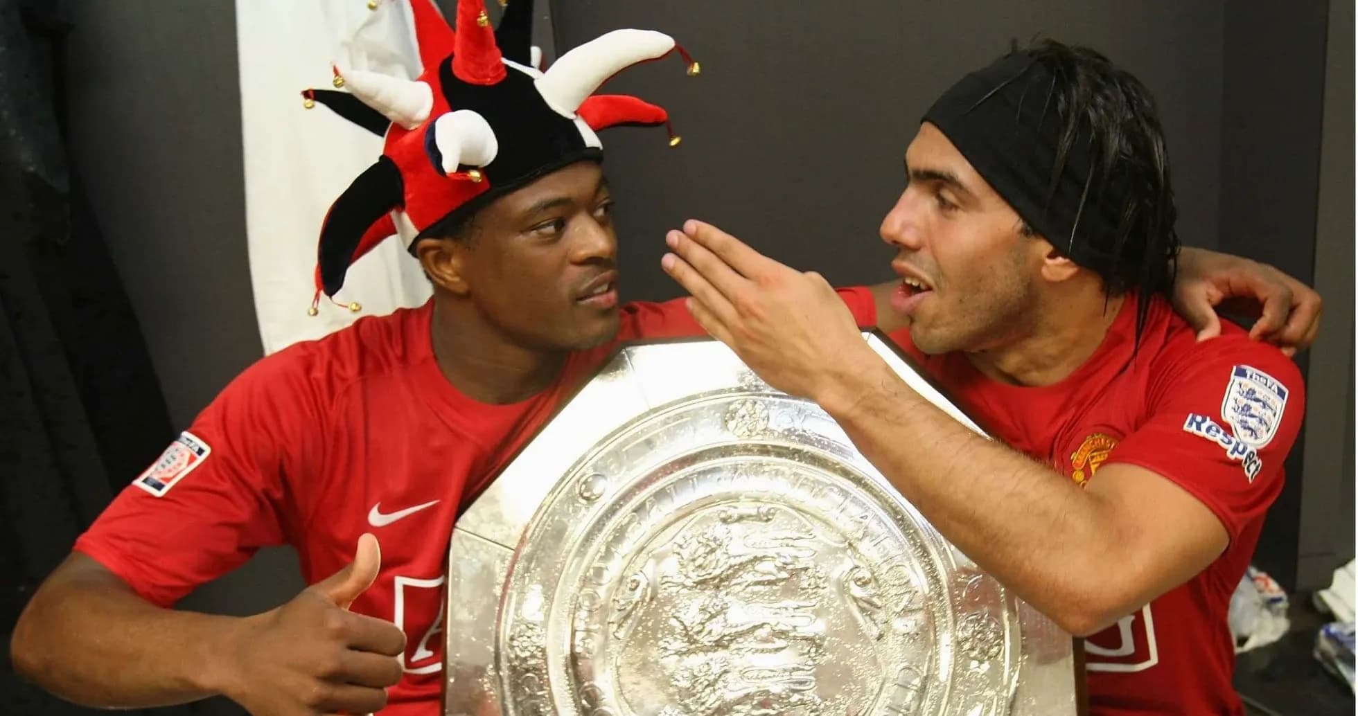 Two players celebrating with a trophy in locker room