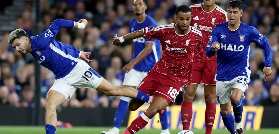 Ipswich player challenging Liverpool defender for the ball