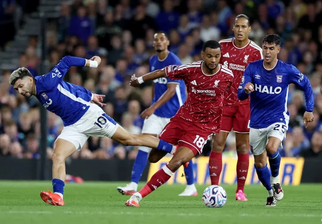 Ipswich player challenging Liverpool defender for the ball