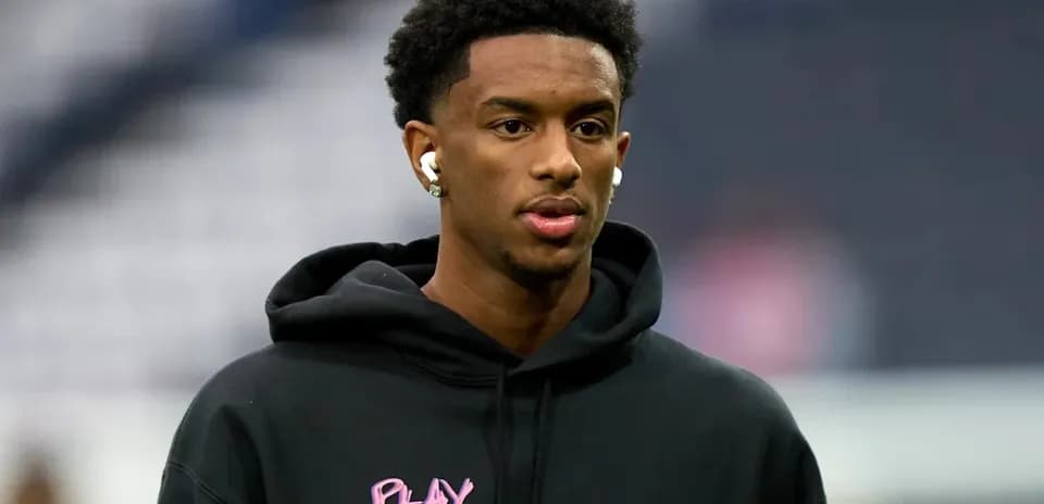 Player wearing earbuds and black hoodie before game