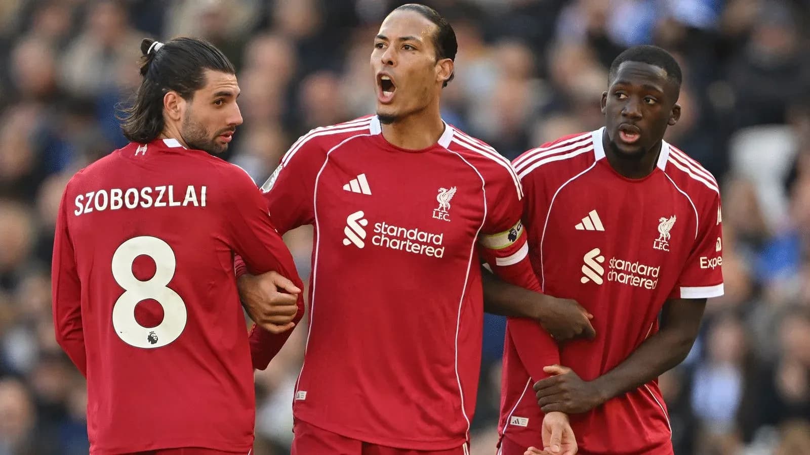 Three Liverpool players discussing during a match