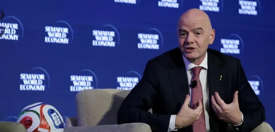 Gianni Infantino speaking at a conference with a football