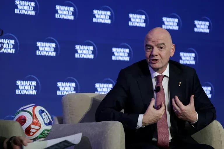 Gianni Infantino speaking at a conference with a football