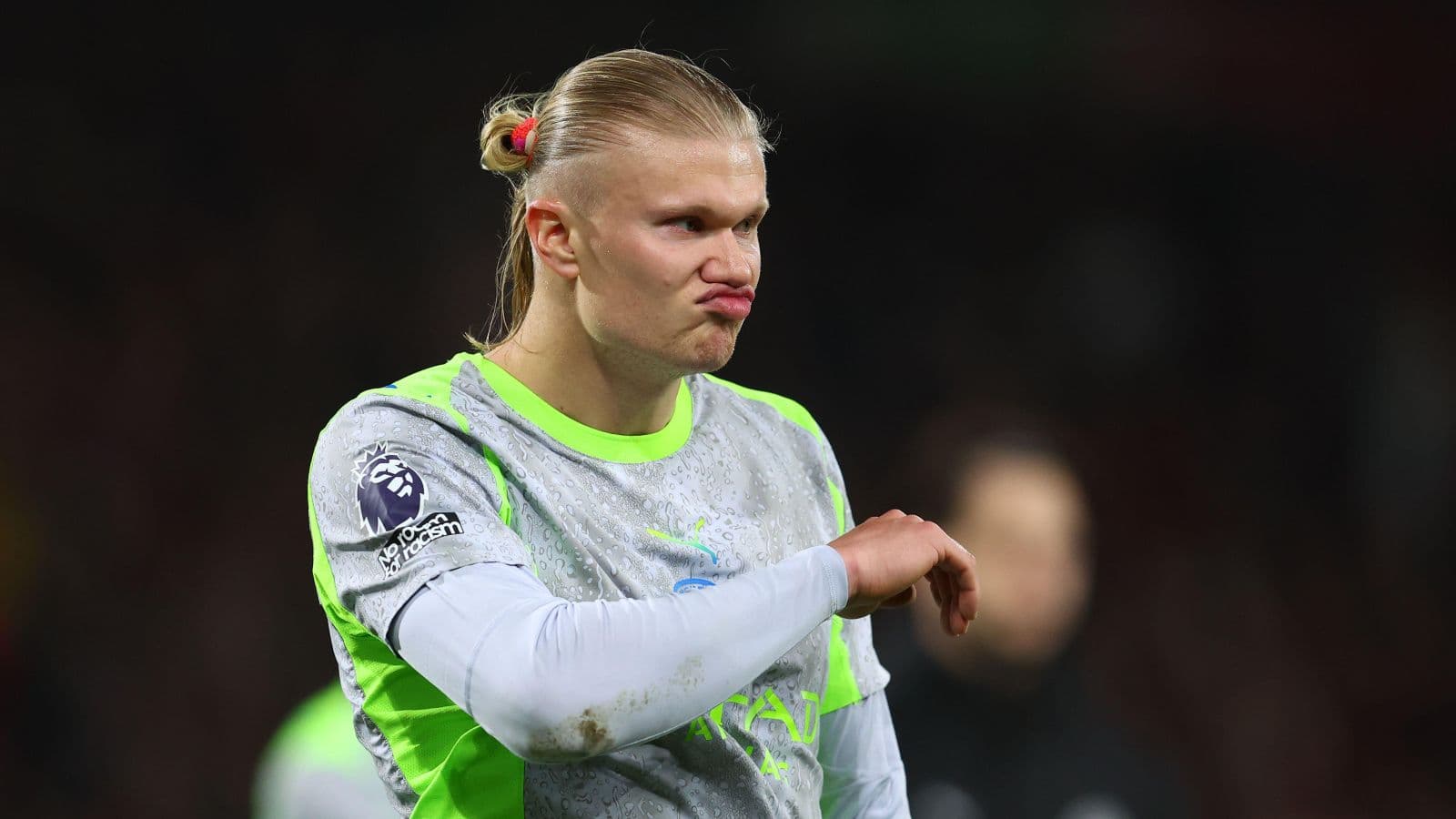 Player in green kit gesturing during match warm-up