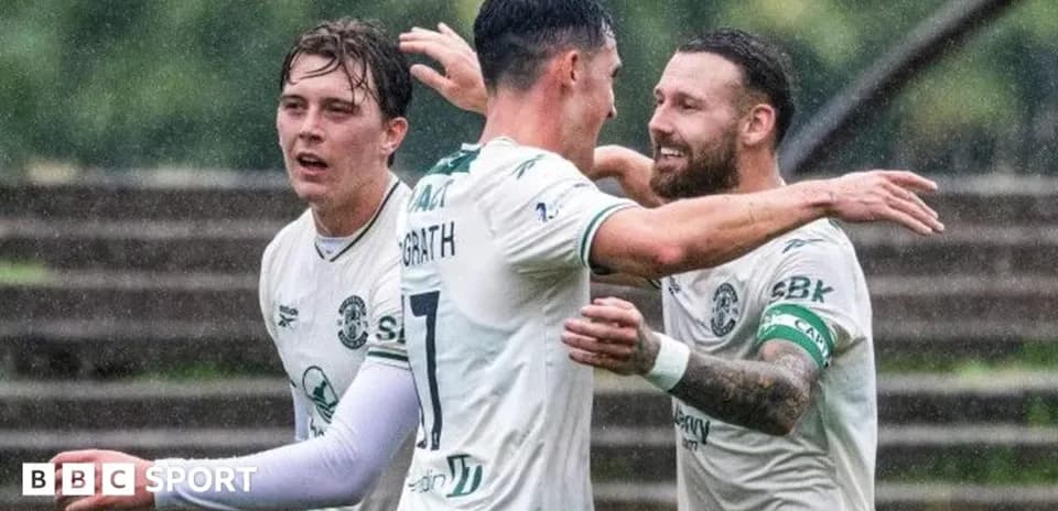 Players celebrating a goal in a rain-soaked match