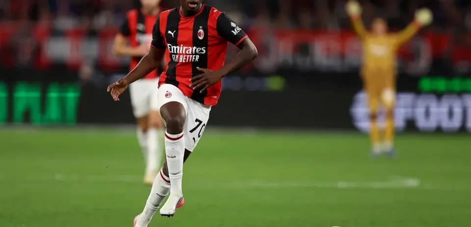 Player in AC Milan kit running with ball on field