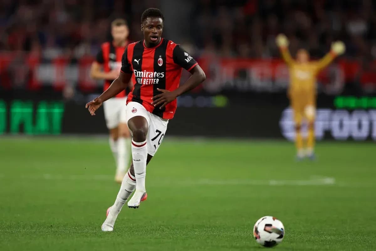 Player in AC Milan kit running with ball on field