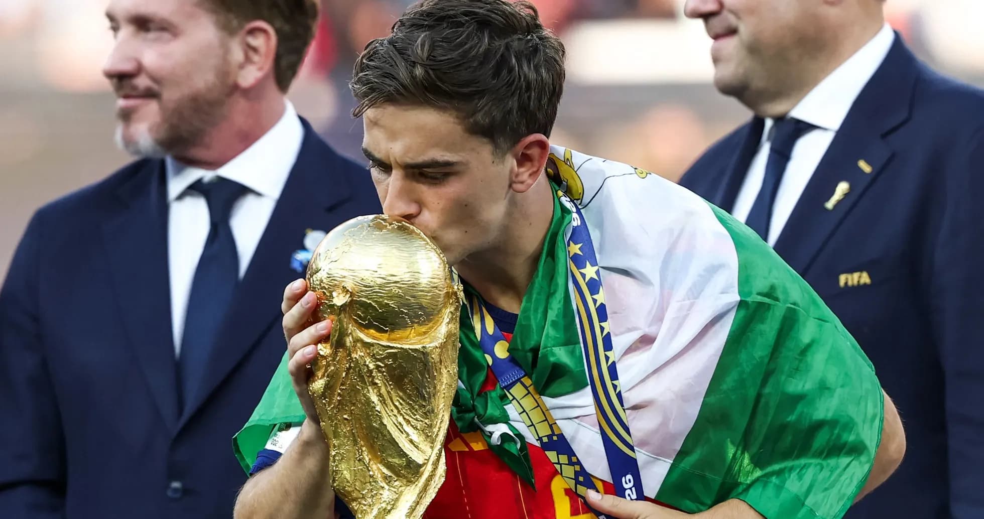 Player kissing the World Cup trophy with flags