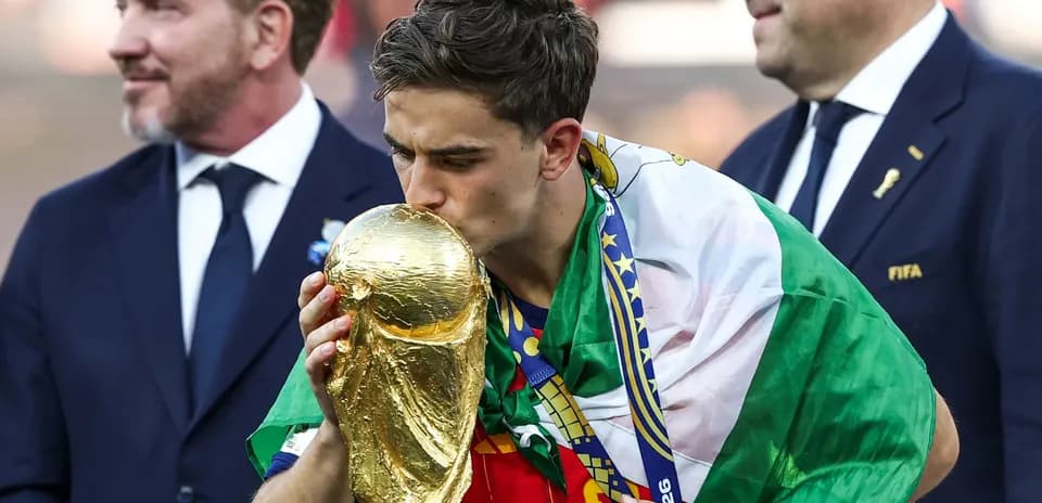 Player kissing the World Cup trophy with flags