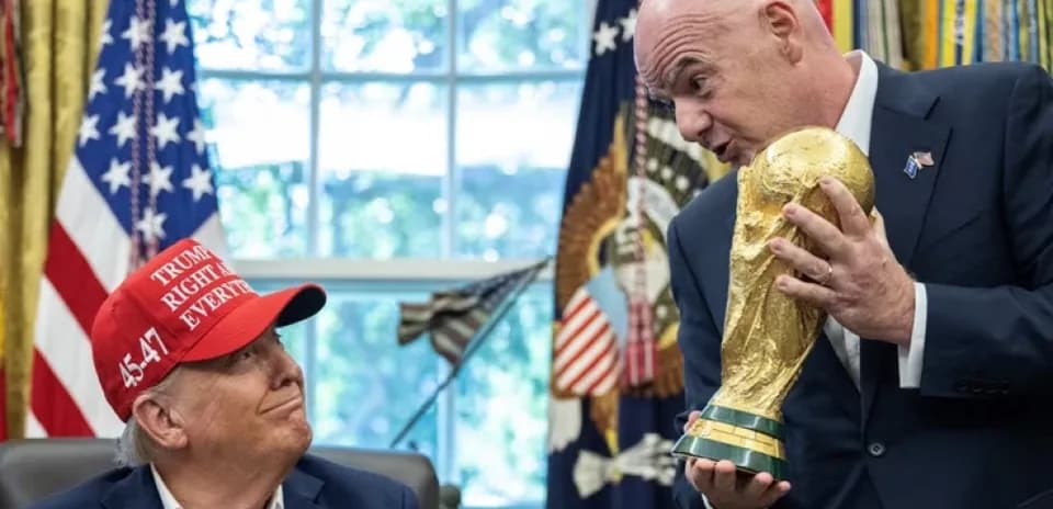 Man holding FIFA World Cup trophy with another man