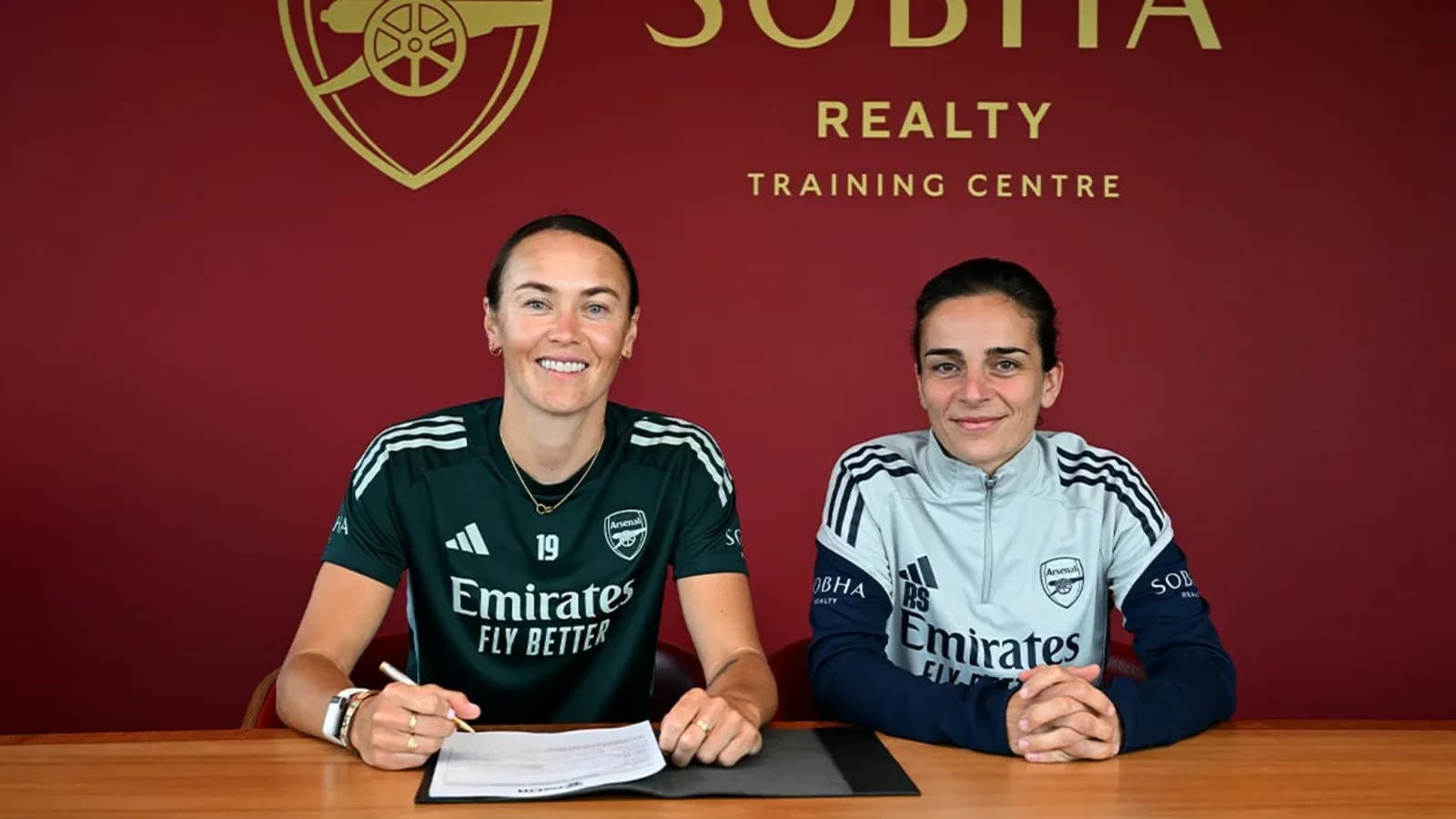 Two players signing contracts at Arsenal training center