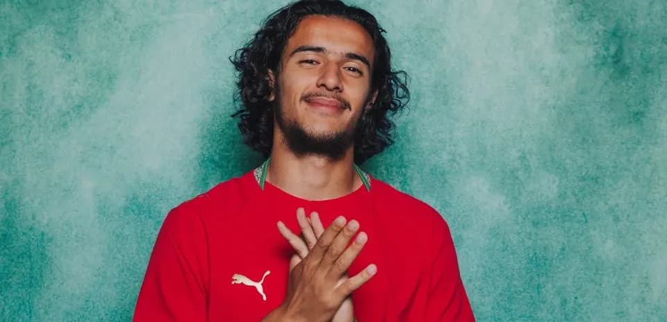 Player posing in red jersey against green background