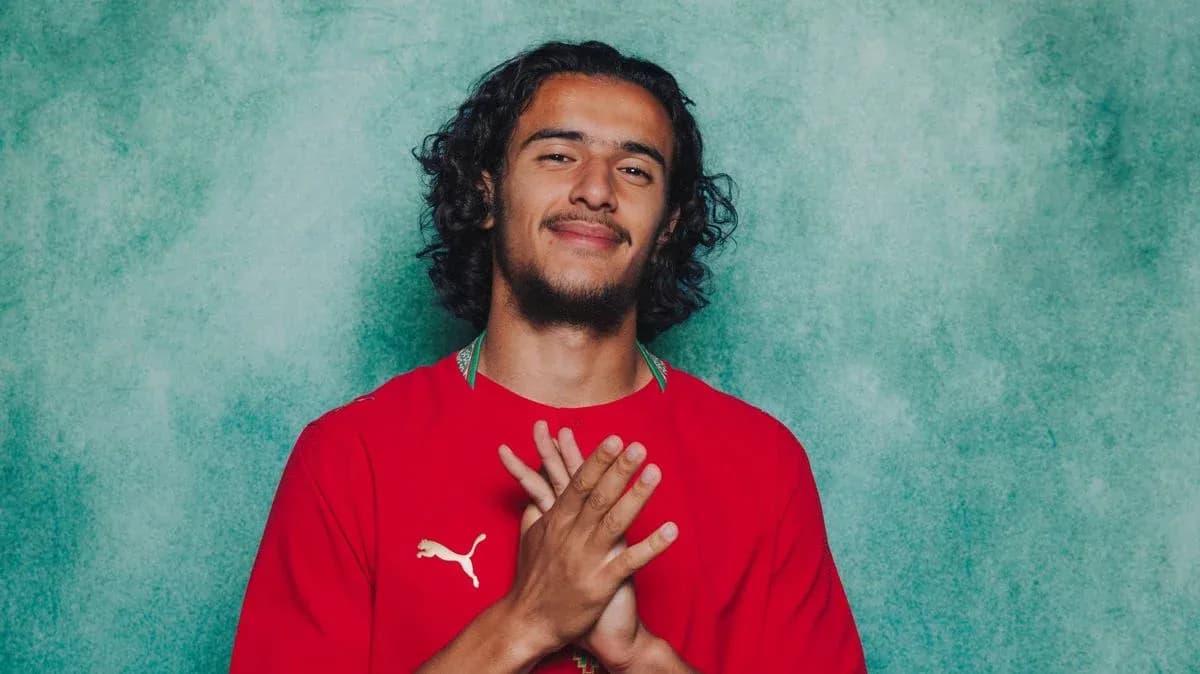 Player posing in red jersey against green background